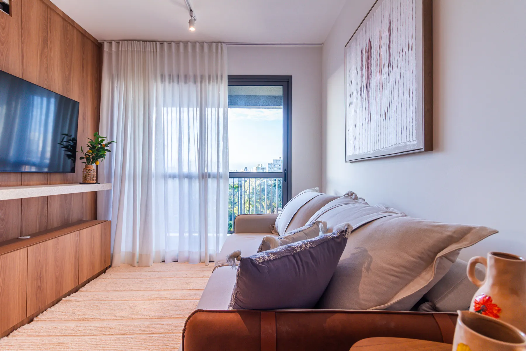 Sala de estar do apartamento decorado de 3 dormitórios, com painel de madeira e iluminação quente